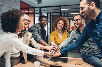 6_team_members_gathered_around_table_with_hands_.jpg