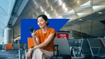 WomanSittingInAirportHoldingPhoneWithSAPAnivilInBackground.jpg