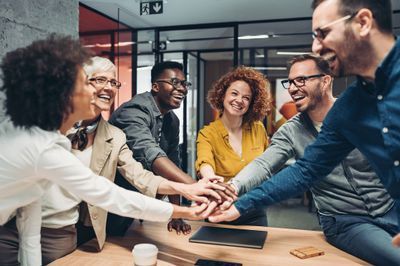 6_team_members_gathered_around_table_with_hands_.jpg